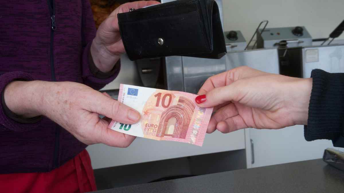 Persona entregando un billete de 10 euros en efectivo, representando la Ley 7/2012 y las multas del 25%