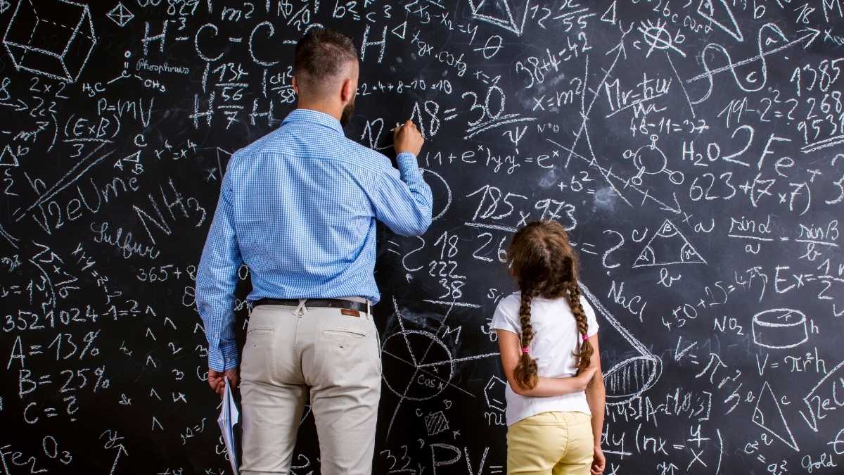 Profesor de Secundaria en Madrid explicando matemáticas en la pizarra junto a una alumna