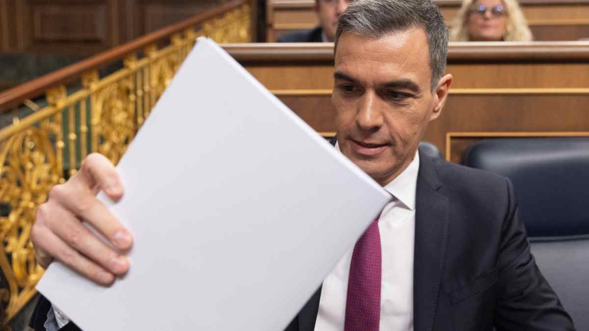 Pedro Sánchez en el Congreso revisando documentos sobre ayudas económicas del Gobierno.