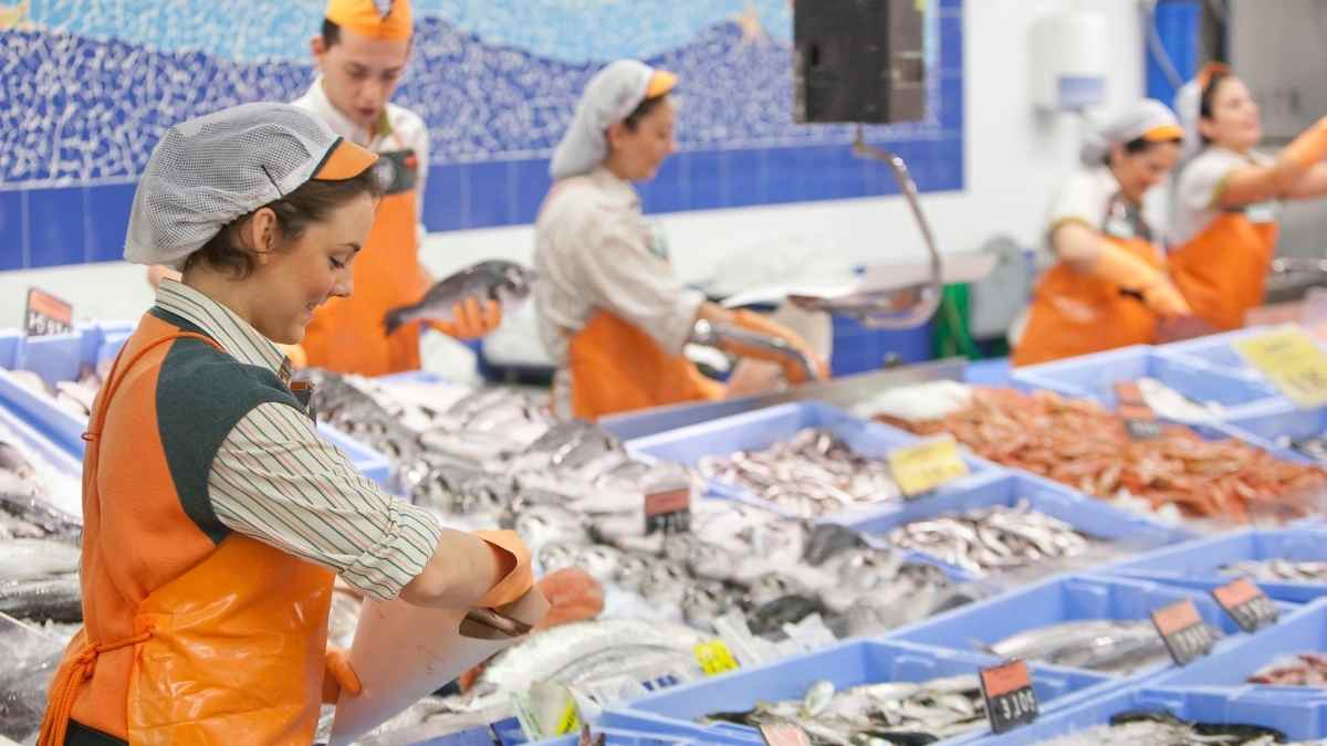 Trabajadora de la pescadería de Mercadona manipulando pescado fresco en el mostrador.