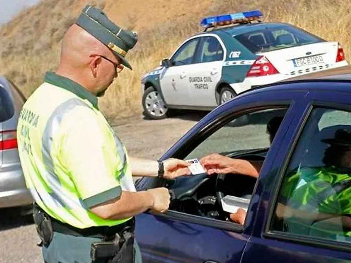 Agente de la Guardia Civil de Tráfico revisando documentación a un conductor durante un control en carretera