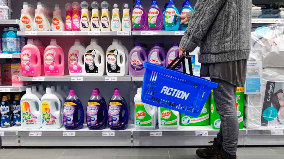 Cliente con cesta azul de Action elige detergentes en el pasillo de limpieza del nuevo supermercado holandés en España