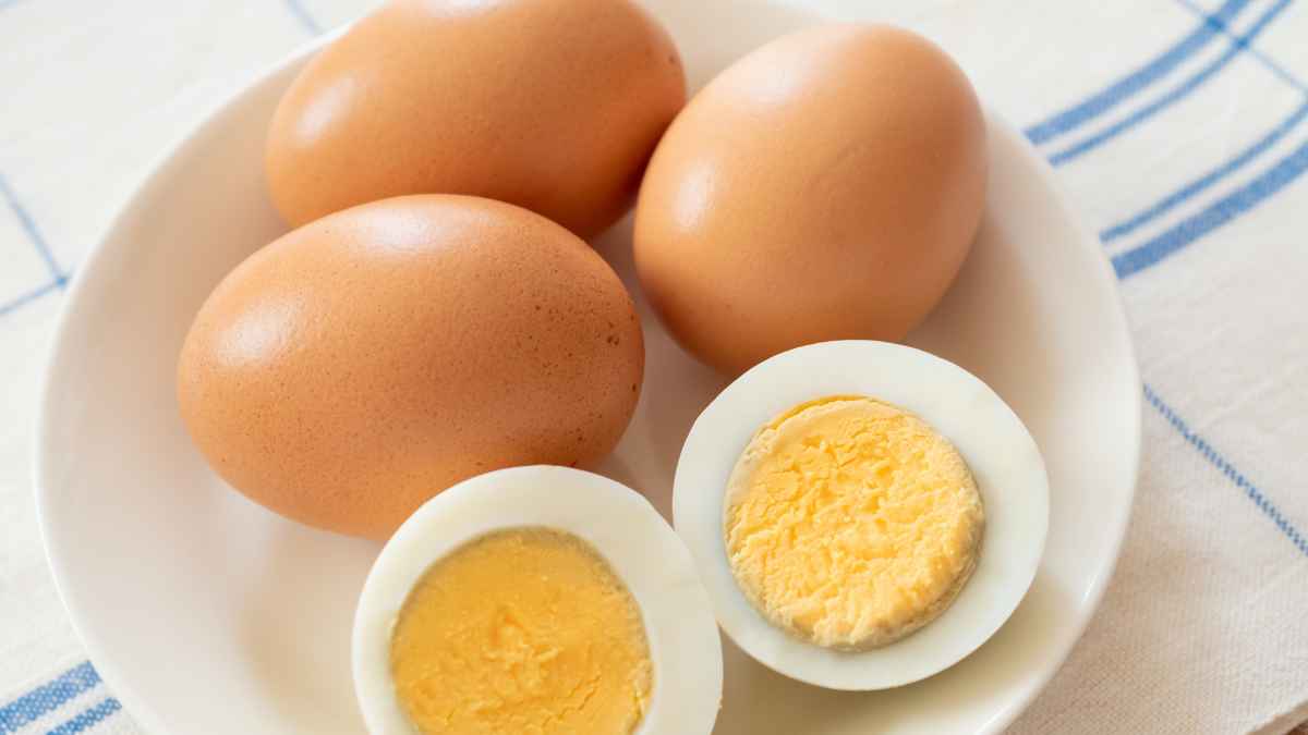 Huevos cocidos en un plato, uno cortado por la mitad, tras agitarse en agua fría para pelar sin restos de cáscara