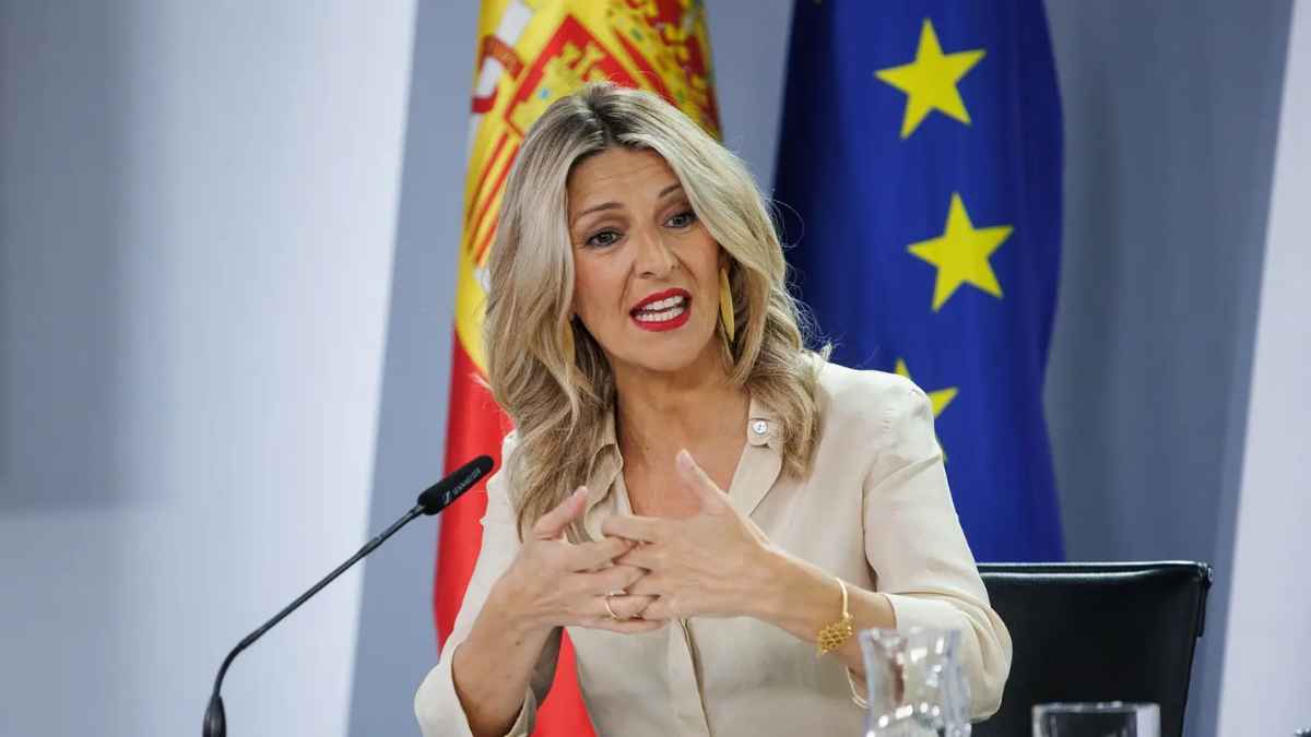 Yolanda Díaz en rueda de prensa con las banderas de España y de la Unión Europea al fondo