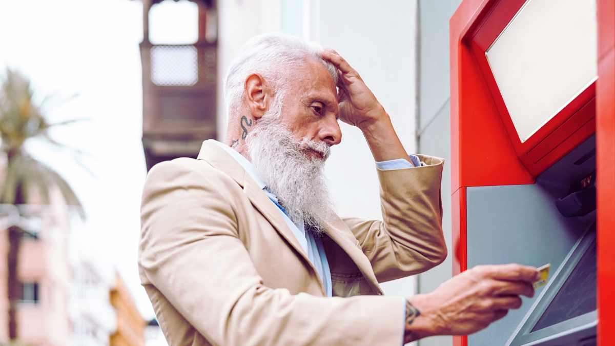Hombre mayor preocupado frente a un cajero automático tras el cierre masivo de cuentas bancarias anunciado para mayo 2025