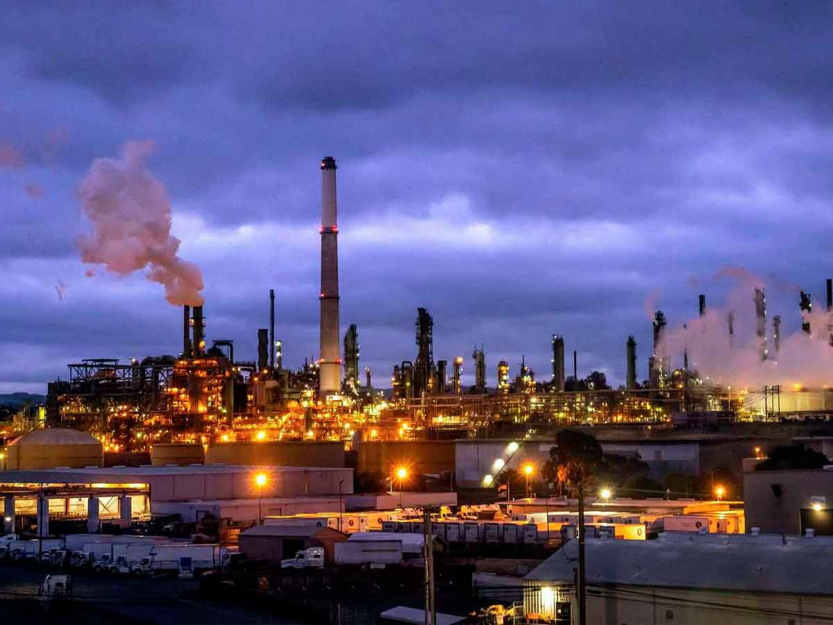 Refinería Valero de Benicia iluminada al anochecer, chimeneas humeantes antes de su cierre definitivo en California