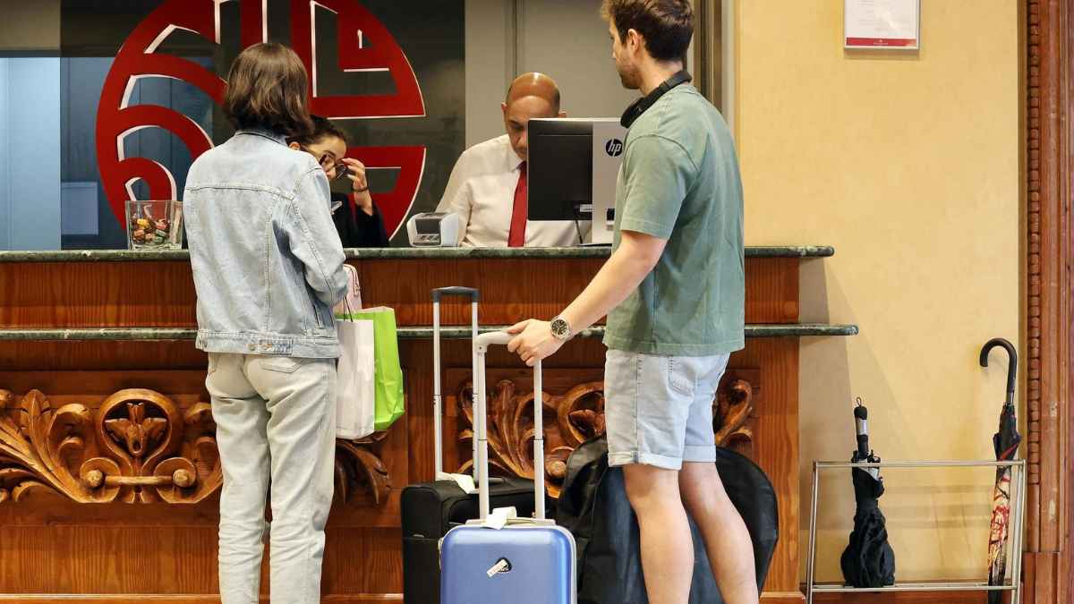 Huéspedes con maletas entregan su DNI en la recepción de un hotel durante el check-in, momento clave para proteger los datos personales