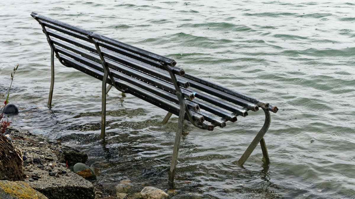 Banco de parque parcialmente sumergido por la subida del nivel del mar en la costa española