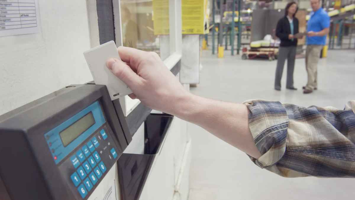 Trabajador fichando con tarjeta en máquina de control de presencia en fábrica para registrar sus pausas en jornada laboral de ocho horas