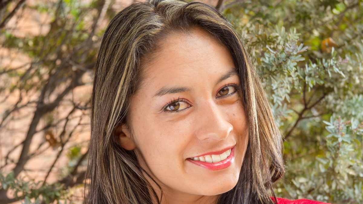 Joven colombiana sonriente que reflexiona sobre la eficiencia laboral de los trabajadores españoles