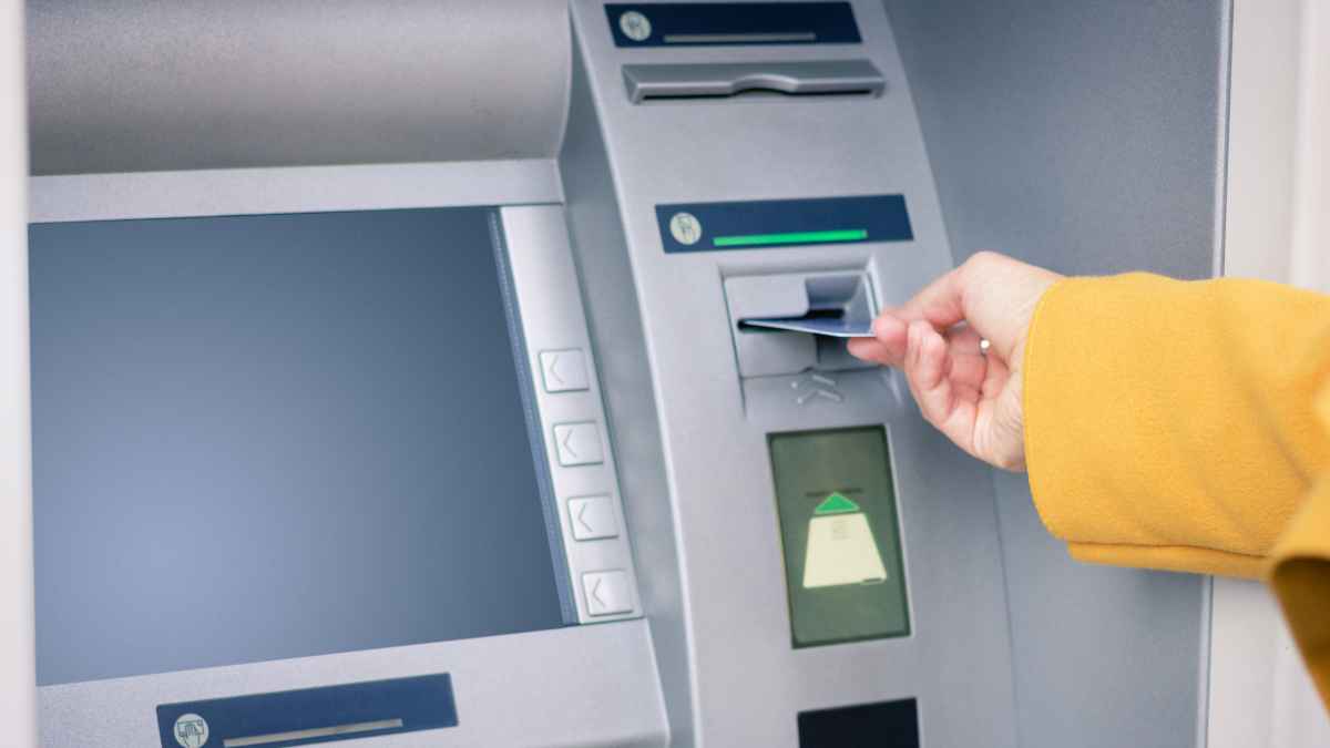 Insertando tarjeta de débito en cajero automático bajo control de Hacienda y movimientos de dinero vigilados