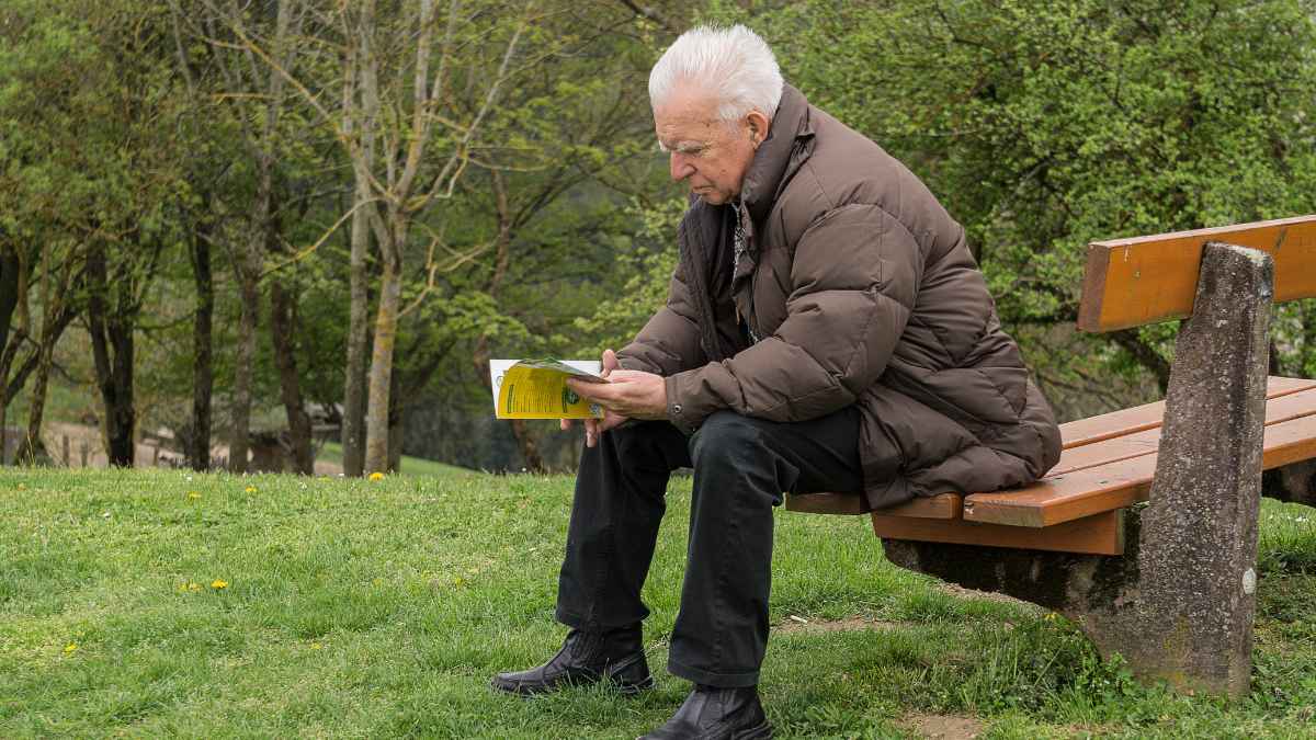 Jubilado de 67 años desalojado tras ayudar a su hija lee documentos en un banco del parque