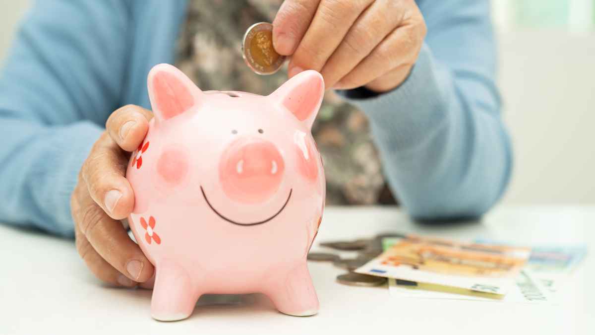Jubilado introduce una moneda en una hucha cerdito para ilustrar la pensión de casi 3.000 euros al mes