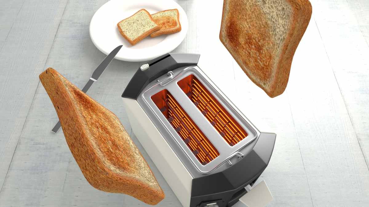 Tostadora tradicional expulsando rebanadas de pan tostado sobre la mesa