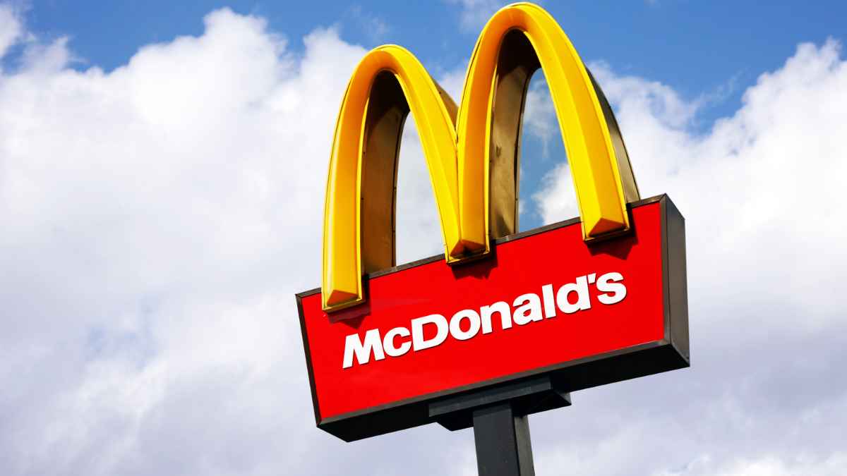 Cartel exterior con los arcos dorados y el logo de McDonald’s sobre un cielo parcialmente nublado