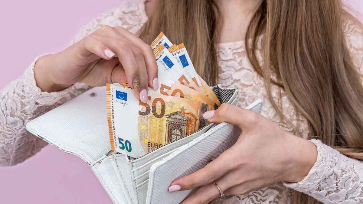Mujer sacando billetes de 50 € de una cartera blanca