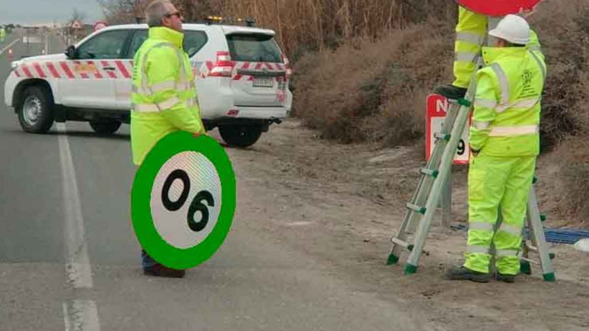 Operarios viales colocan la nueva señal circular de velocidad recomendada, borde verde, 60 km/h, en una carretera para probar su eficacia.