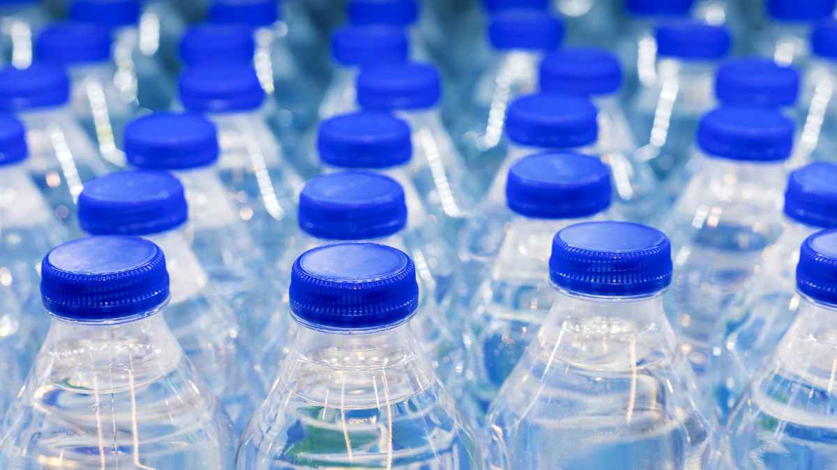 Botellas de agua embotellada con tapones azules en un supermercado; la OCU elige la mejor