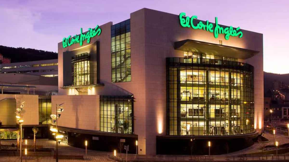 La fachada del corte inglés iluminada al anochecer mostrando sus grandes ventanales y logo verde