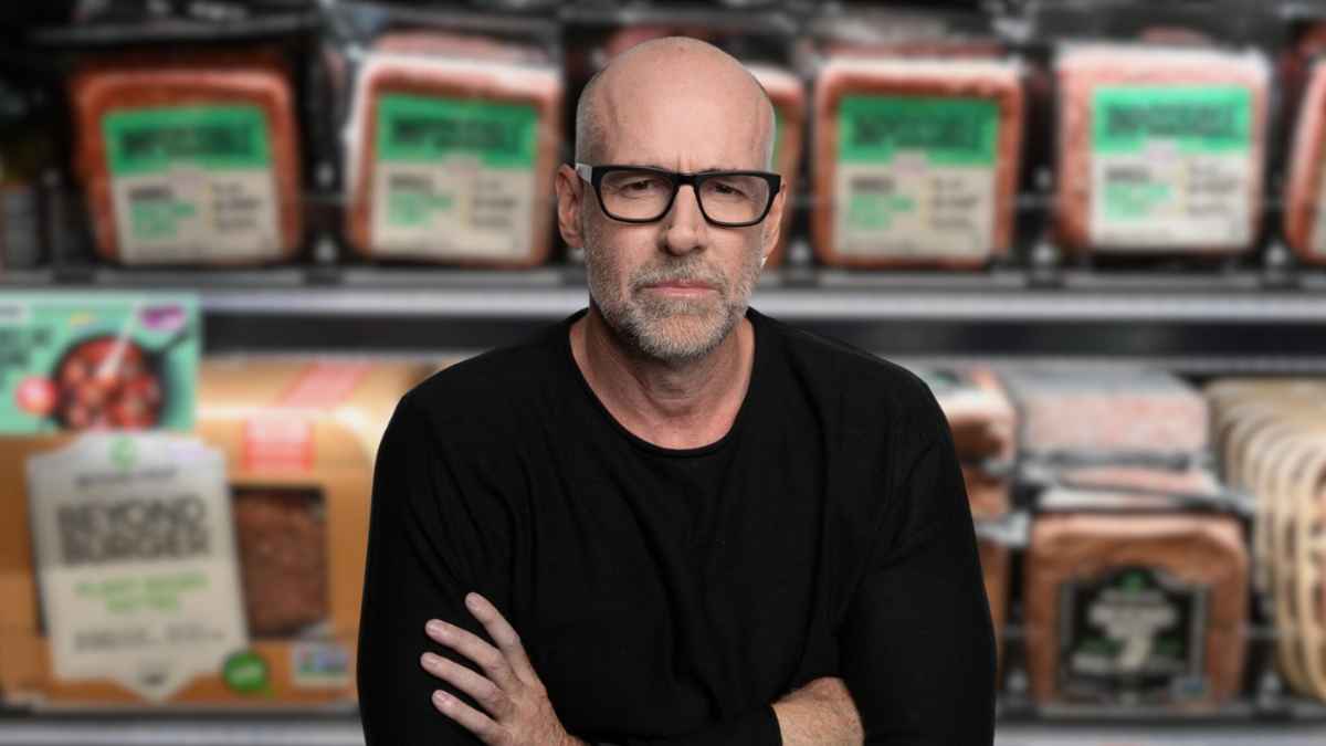 Profesor Scott Galloway con los brazos cruzados frente a estanterías de productos empaquetados en un supermercado