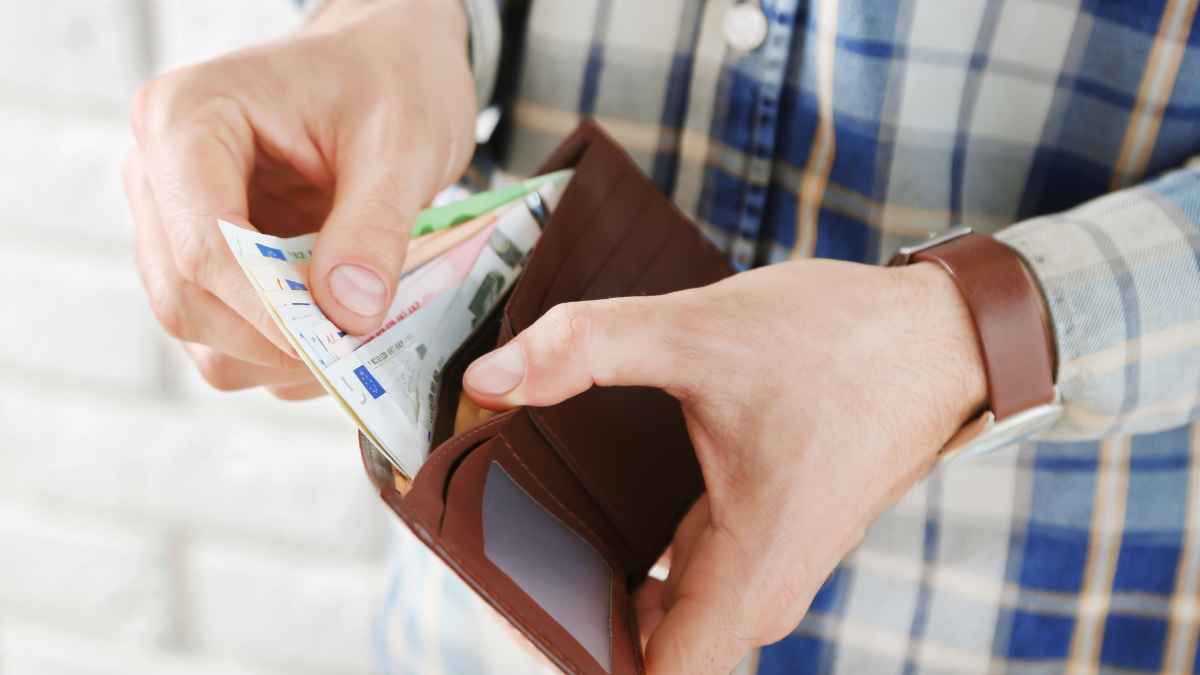 Hombre sacando billetes de su cartera para guardar dinero de reserva en casa ante apagones y otras emergencias