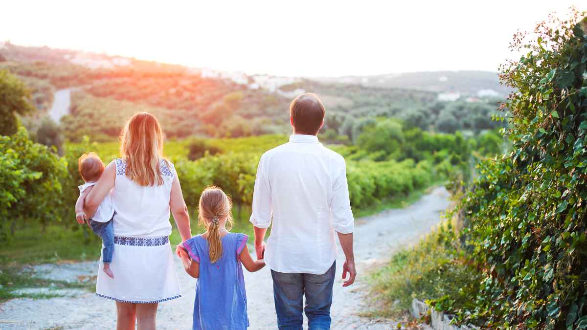 Familia con padres e hijos paseando por un sendero rural al atardecer como ilustración de la ayuda de 1.000 € de la Seguridad Social