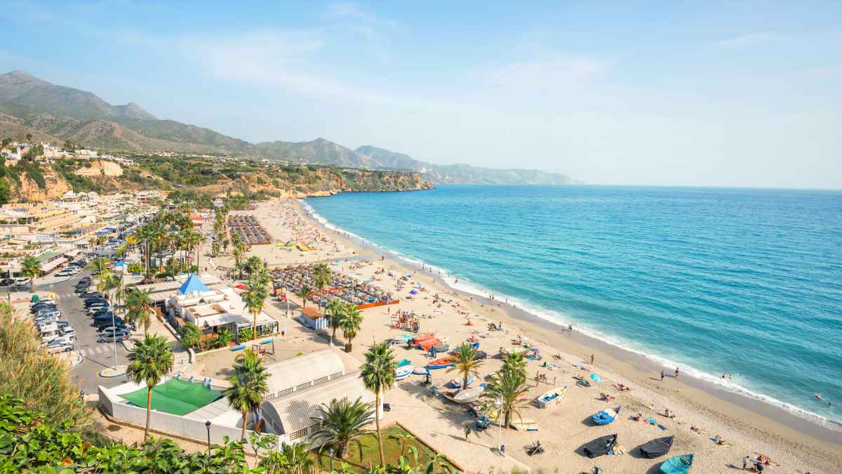 Panorámica de una playa española llena de turistas y palmeras; sin duchas públicas por la sequía y las medidas de ahorro de agua.
