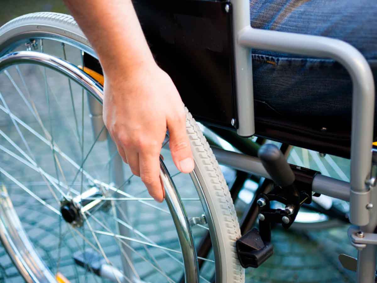 Mano sobre la rueda de una silla de ruedas, símbolo de beneficiarios de cheques por discapacidad de la SSA afectados por la suspensión en mayo 2025