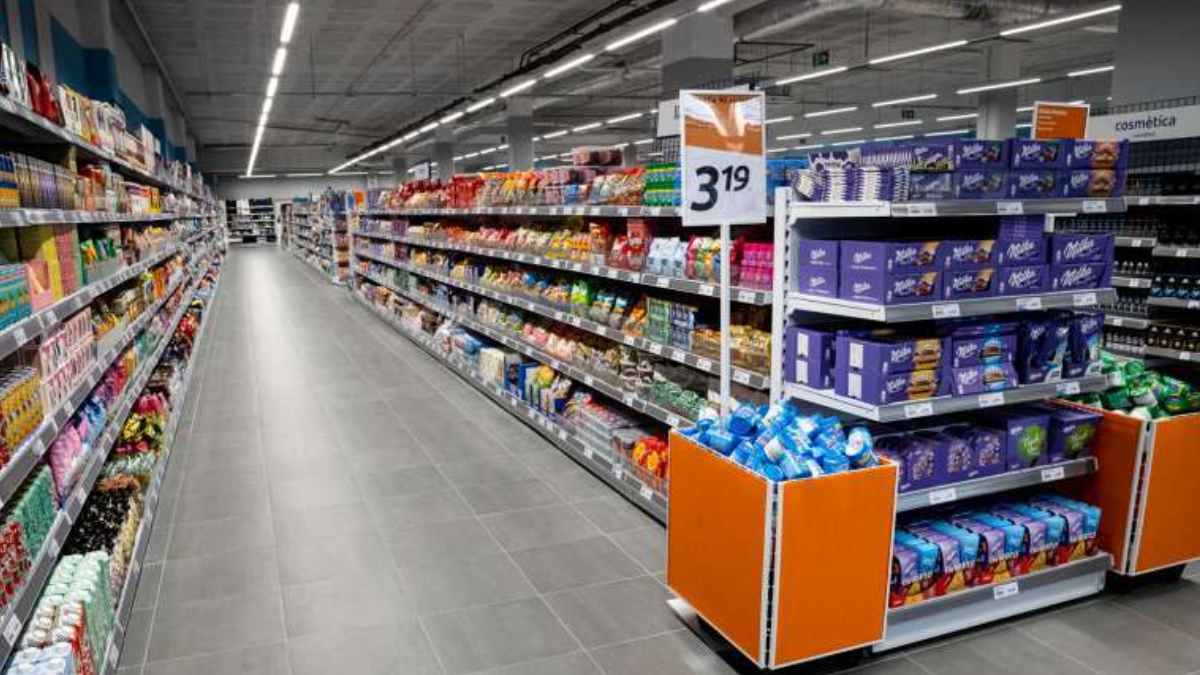 Pasillo de un supermercado Action con estanterías llenas de productos y señal de precio, cadena que compite con Mercadona y Carrefour