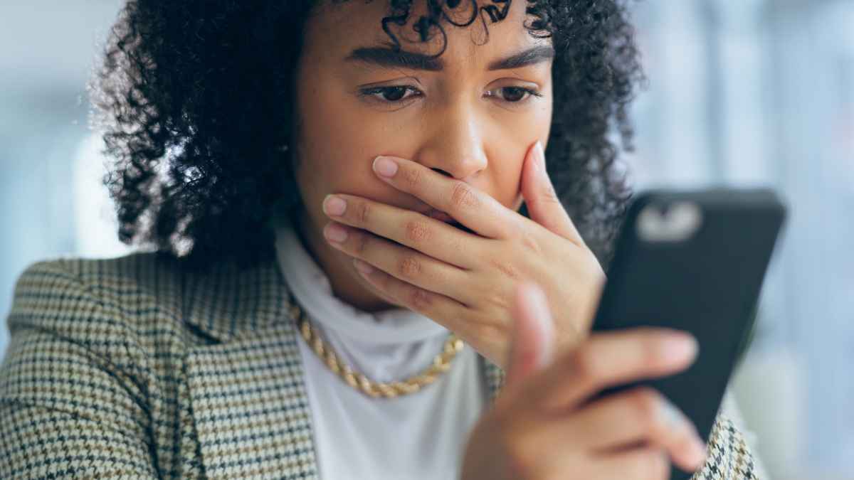 Mujer preocupada revisa su teléfono móvil tras posible fraude de SIM swapping