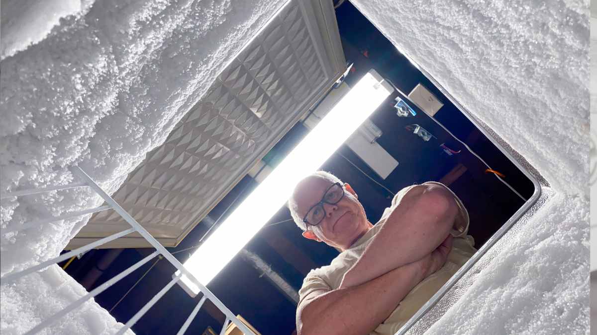 Hombre revisa congelador cubierto de hielo antes de aplicar truco de papel aluminio para descongelar rápido