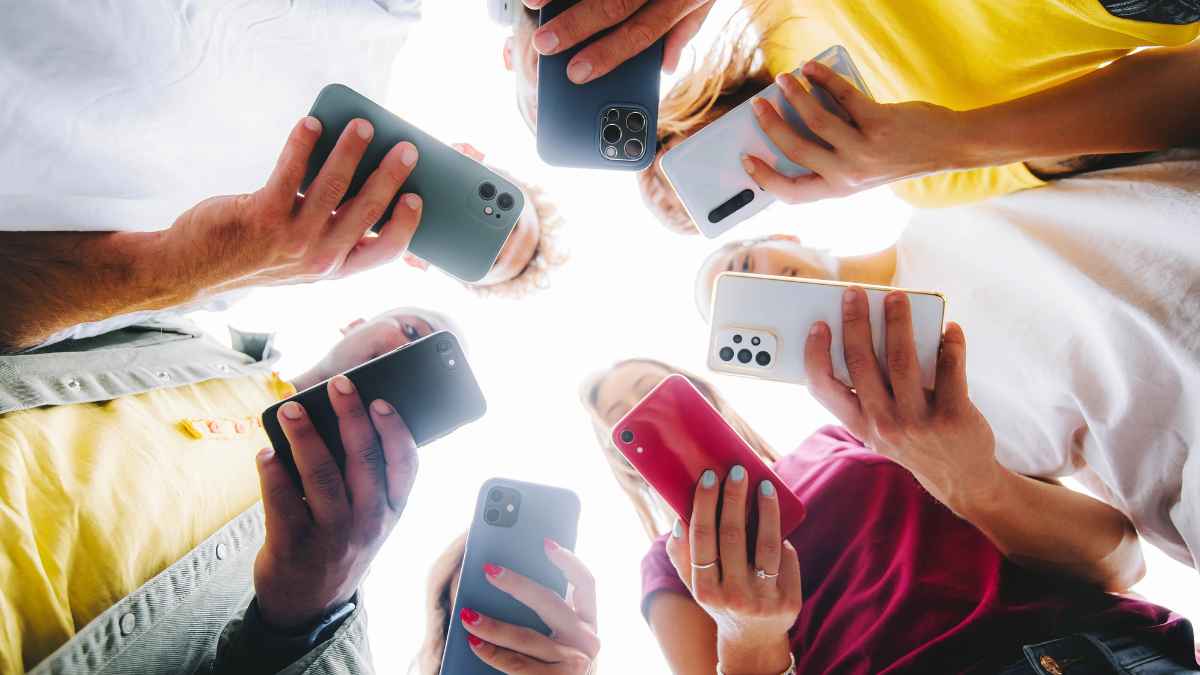 Grupo de jóvenes mirando sus smartphones en círculo, símbolo del fin del móvil antes de 2030 según Nokia