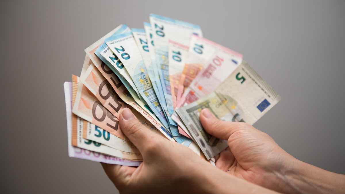 Manos contando billetes de euro, aviso oficial del SEPE sobre la ayuda para quienes ganan menos de 890 euros