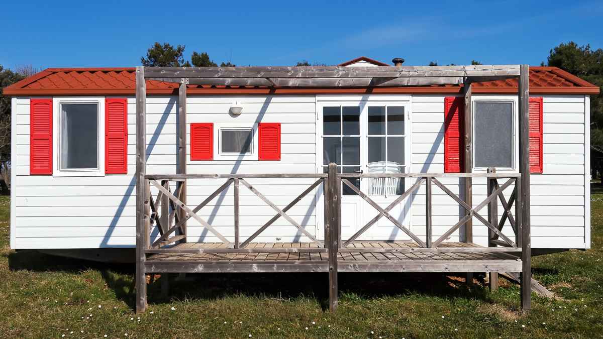 Casa prefabricada blanca con contraventanas rojas y porche de madera, instalada sin licencia en suelo protegido de El Molar.
