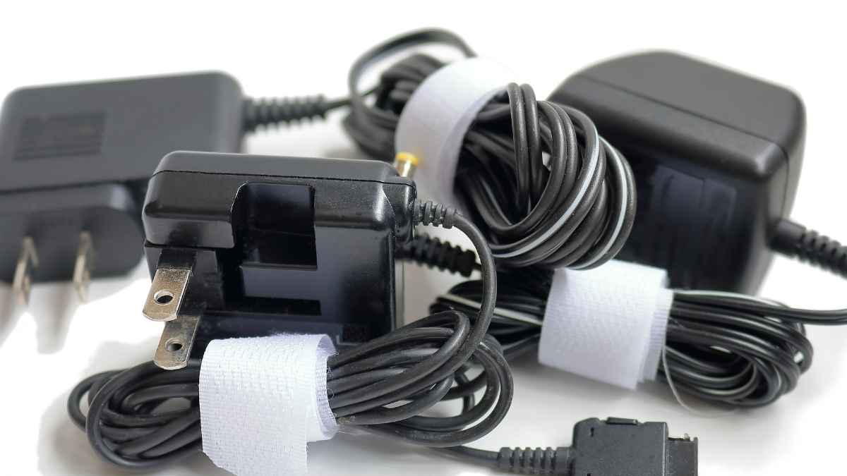 Tres cargadores antiguos de móvil con los cables enrollados, listos para reciclar en soluciones domésticas económicas y sostenibles