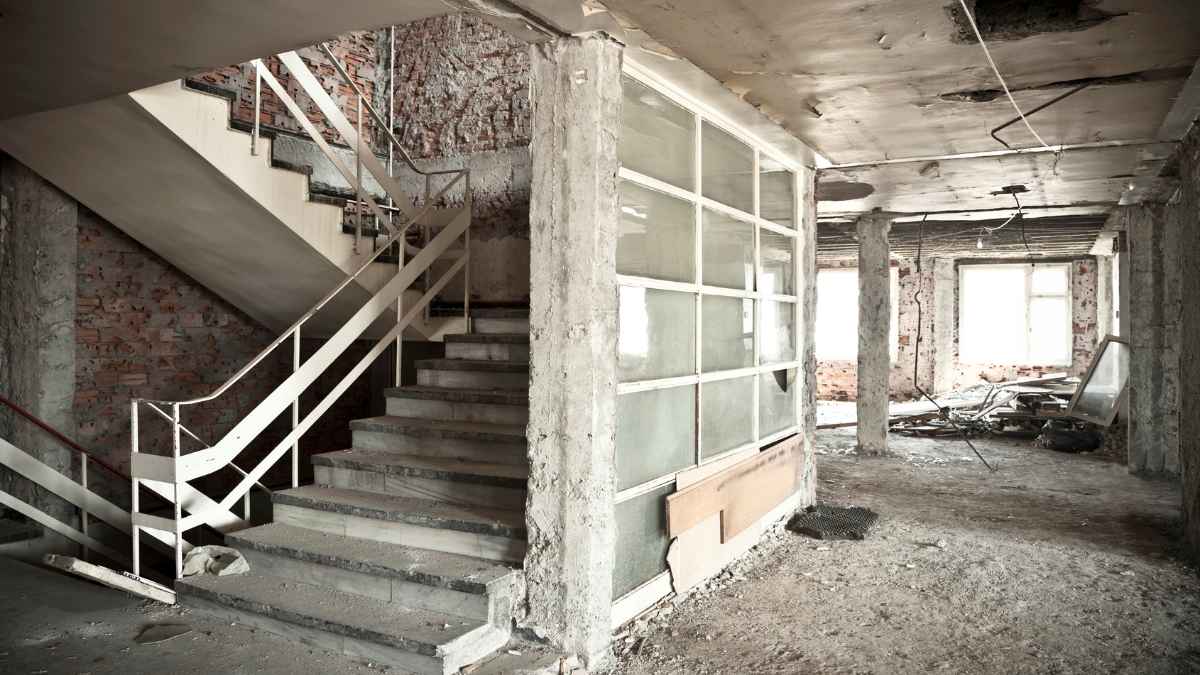 Interior en ruinas de la casa vendida por los ganadores del Euromillones, con escalera dañada, escombros y paredes sin revestir.