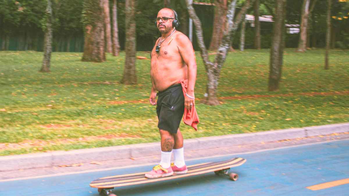 Hombre sin camiseta montando en patineta en espacio público, ejemplo de conducta sancionada en algunas ciudades en verano