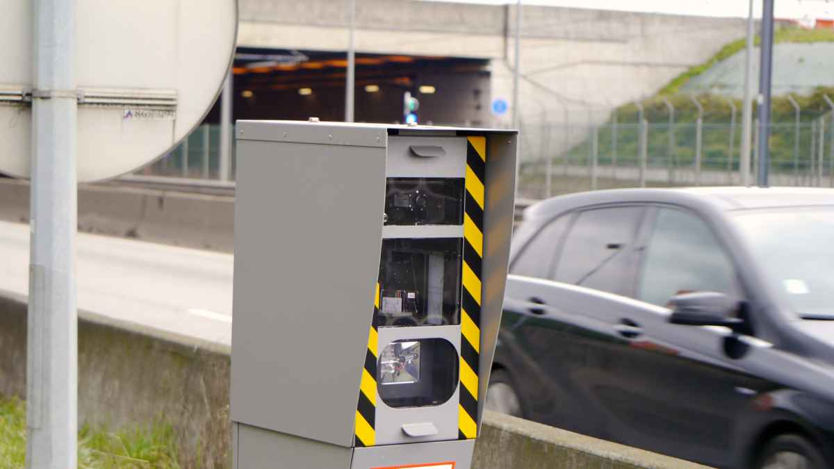 Radar fijo de velocidad en carretera junto a un coche en movimiento
