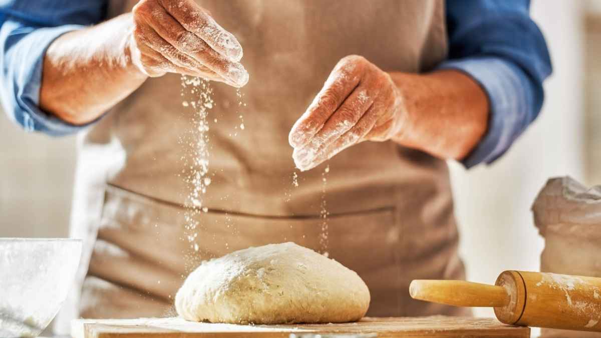 Panadero de Bizkarra espolvoreando harina sobre la masa antes del cierre de sus tiendas el 30 de junio
