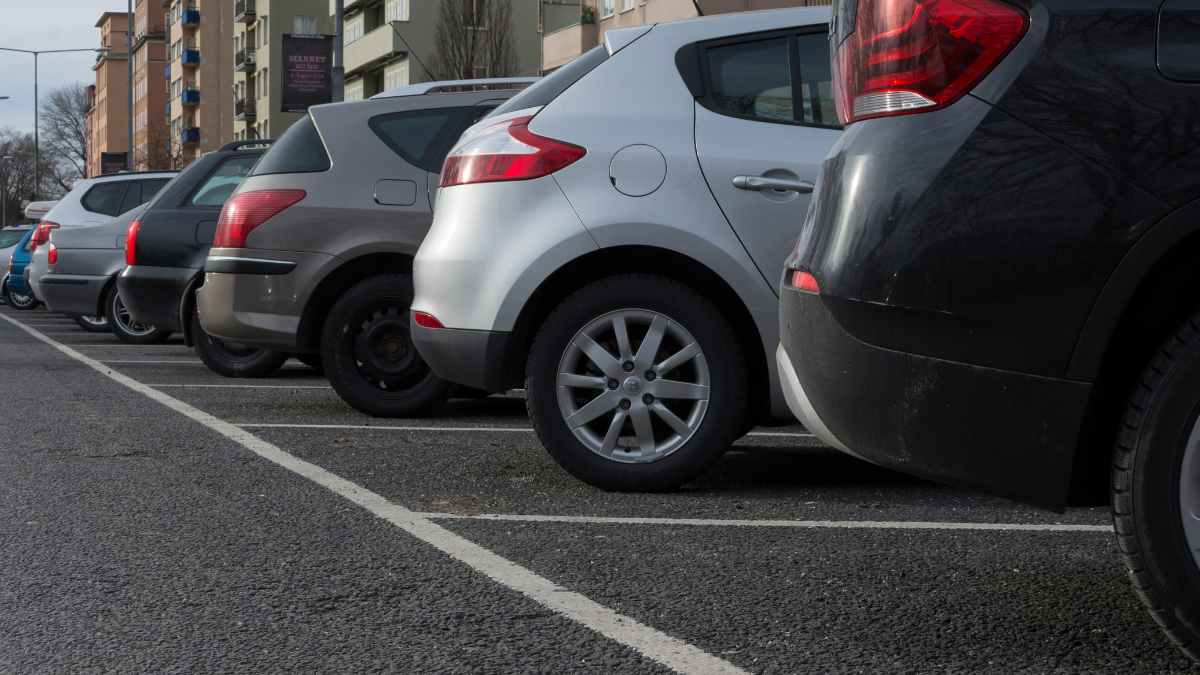 Vehículos estacionados en aparcamiento público donde peatones pueden cometer infracción al guardar plazas según Ley Seguridad Vial