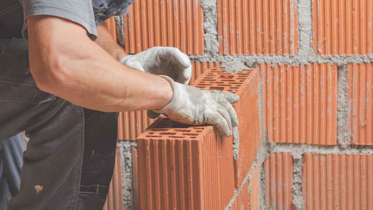 Albañil trabajando con ladrillos tras conseguir pensión incapacidad permanente por hernia discal y amputaciones