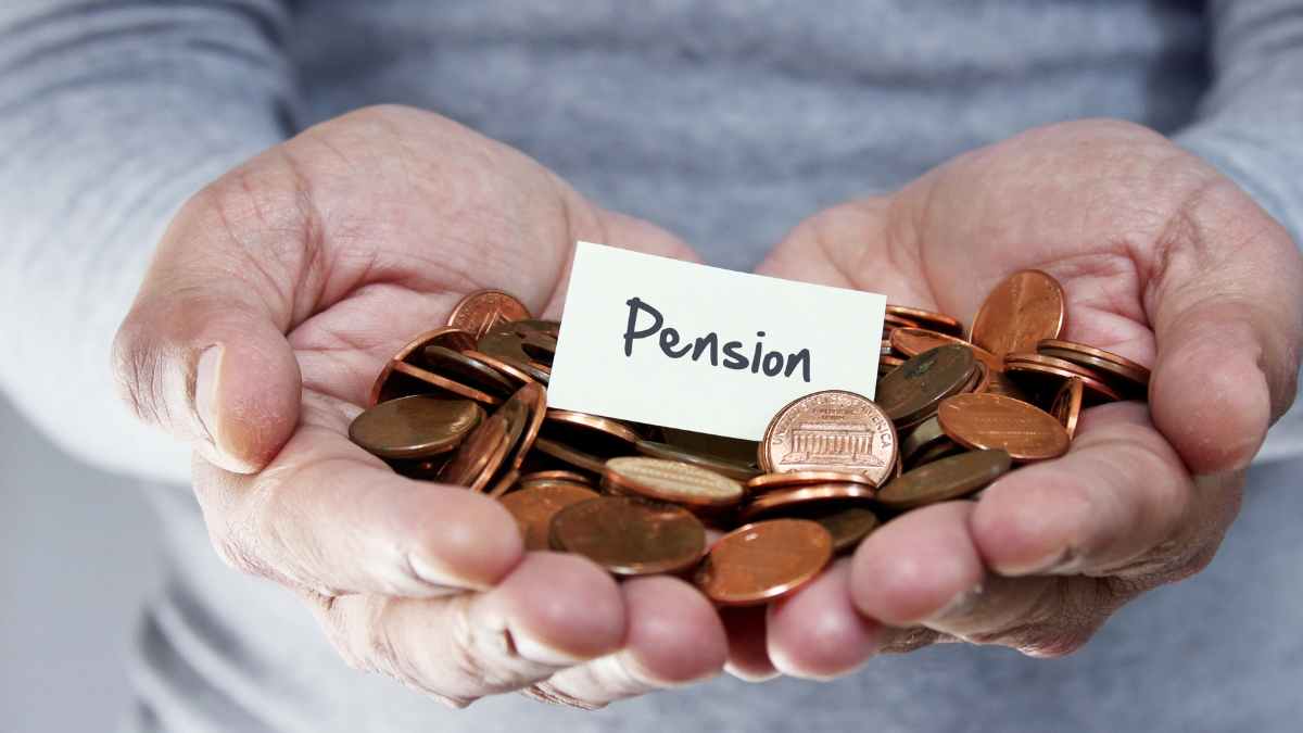 Manos sosteniendo monedas con un papel que dice pensión, ilustrando la reforma propuesta por Paloma Martín sobre pensiones en España