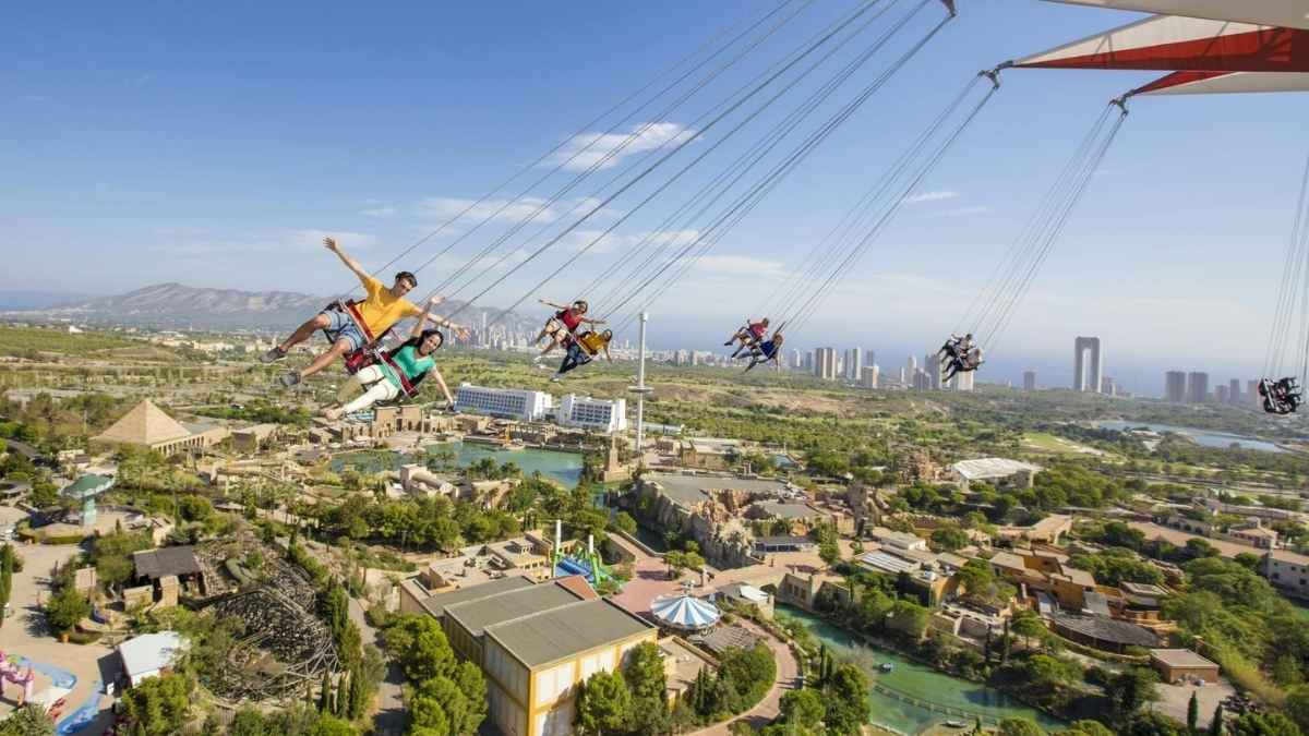 Visitantes en columpio volador contemplan Terra Mítica y el skyline de Benidorm desde las alturas del parque temático valenciano