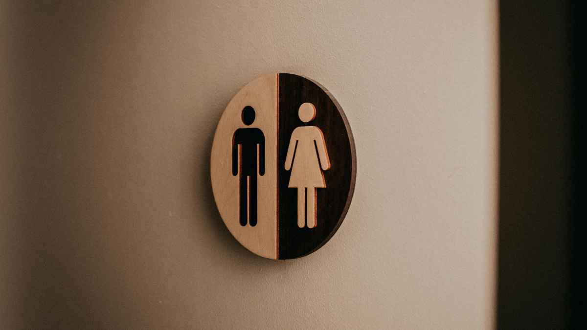 Señal de baño unisex en fábrica automotriz que ilustra el derecho a pausas fisiológicas y la indemnización a un trabajador