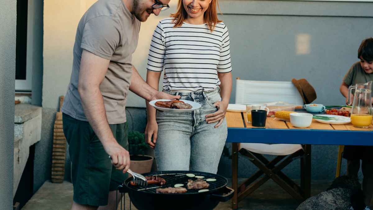 Pareja haciendo una barbacoa en la terraza de casa, actividad ahora multada con hasta 500 euros