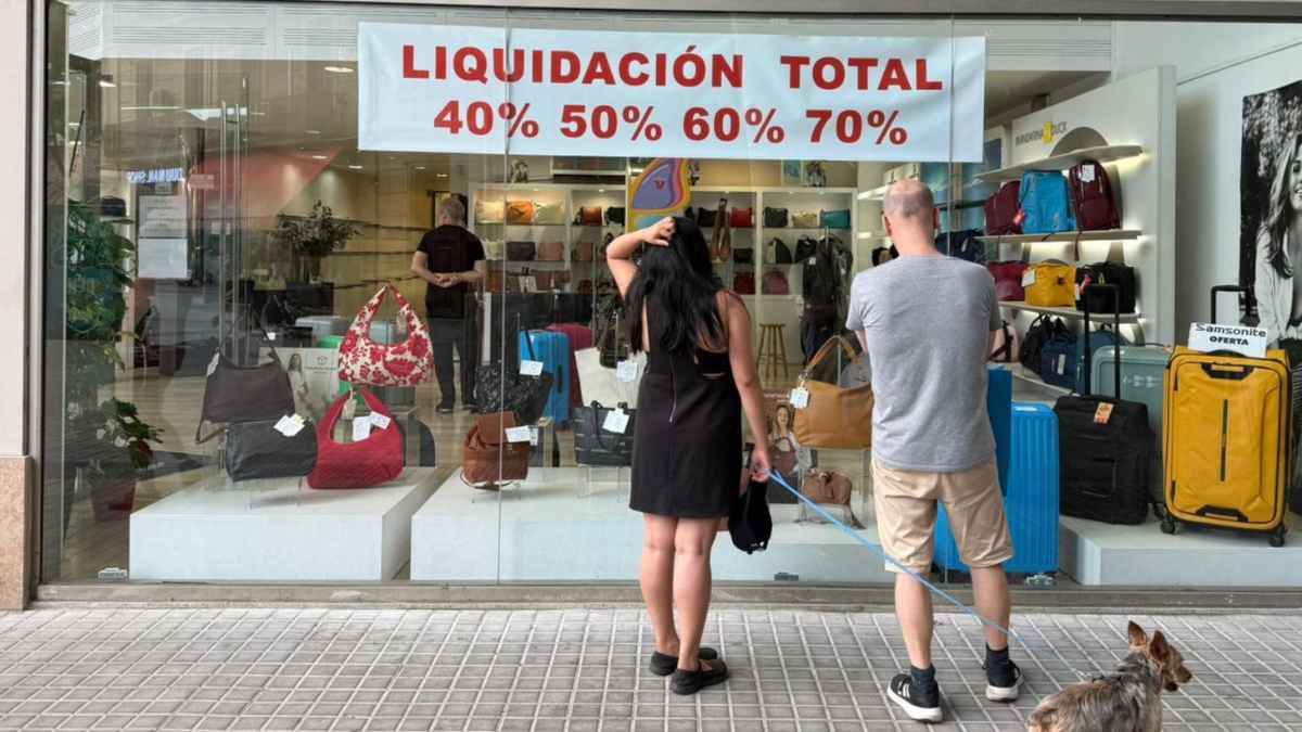 Escaparate de tienda en liquidación total en Barcelona, con descuentos del 40%, 50%, 60% y 70% en bolsos y maletas