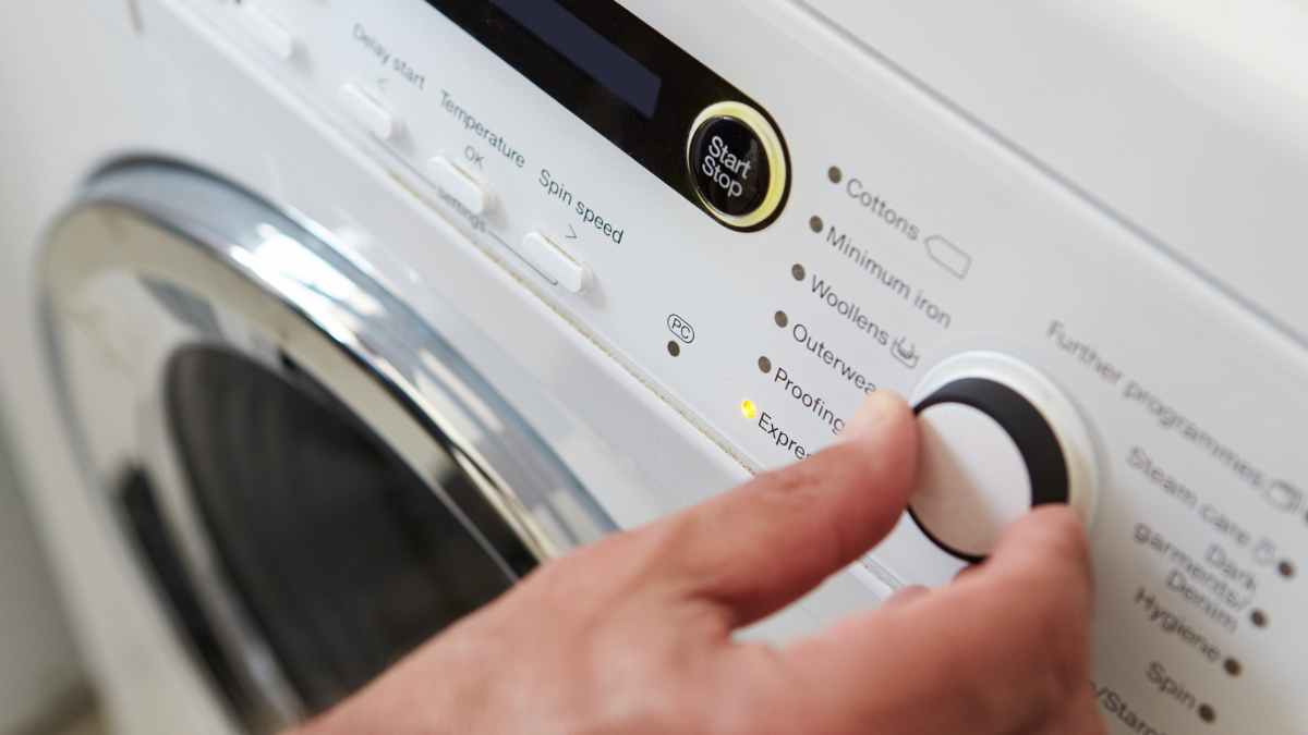 Persona ajustando el botón de centrifugado en una lavadora para secar ropa rápido y ahorrar energía