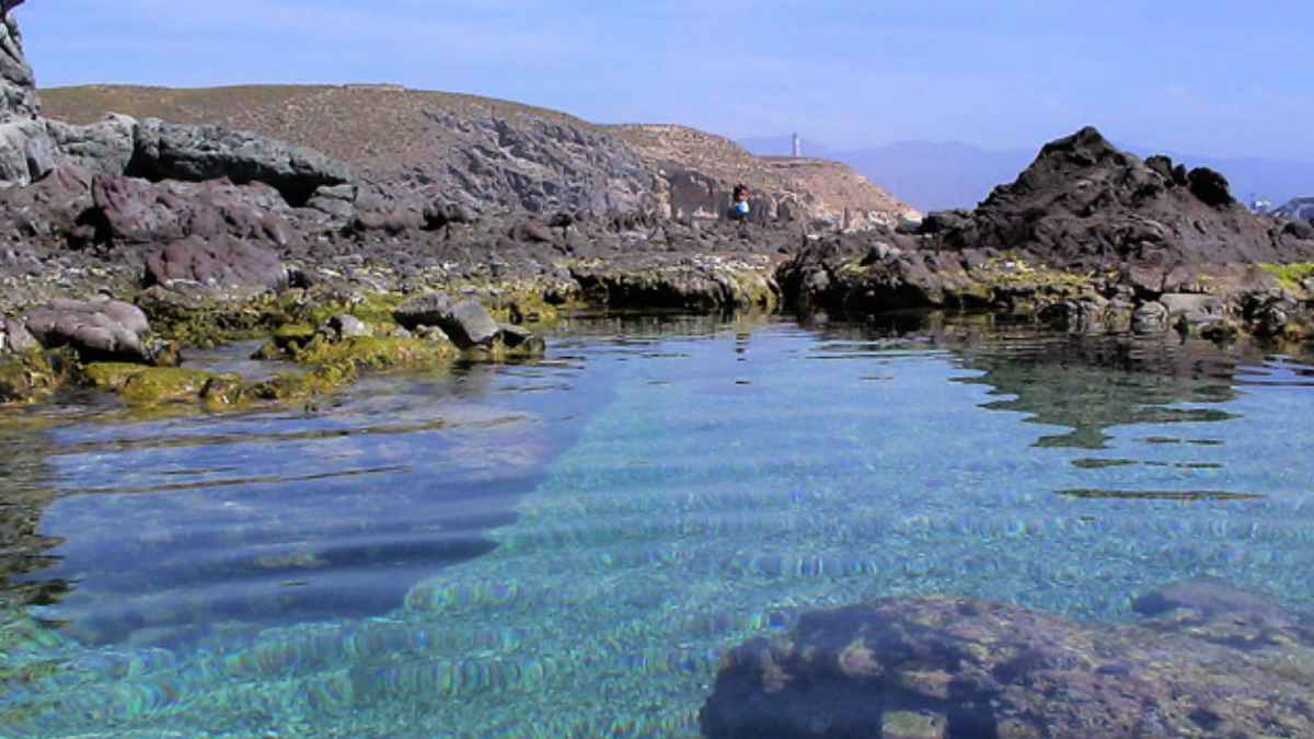 Vista del agua cristalina y rocas volcánicas en una de las calas vírgenes cercanas a Agua Amarga, en el Parque Natural Cabo de Gata, Almería.
