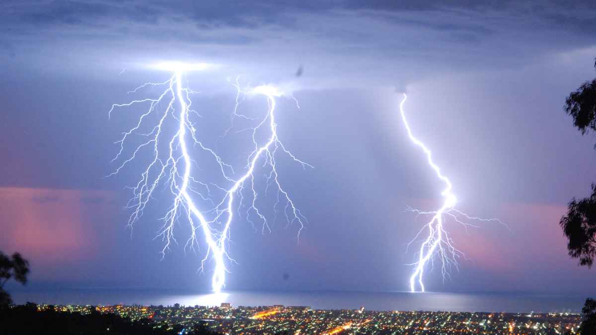 Rayos impactando sobre el mar y una ciudad costera durante una intensa tormenta eléctrica, señal del riesgo para los dispositivos electrónicos del hogar
