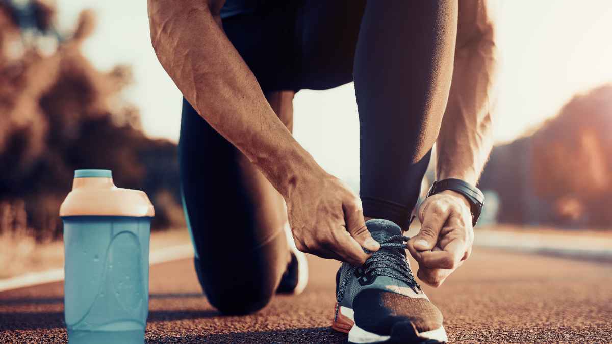 Hombre atándose cordones de zapatillas deportivas antes de entrenar, símbolo del calzado recomendado por el experto Jesús Serrano para evitar daños en los pies.